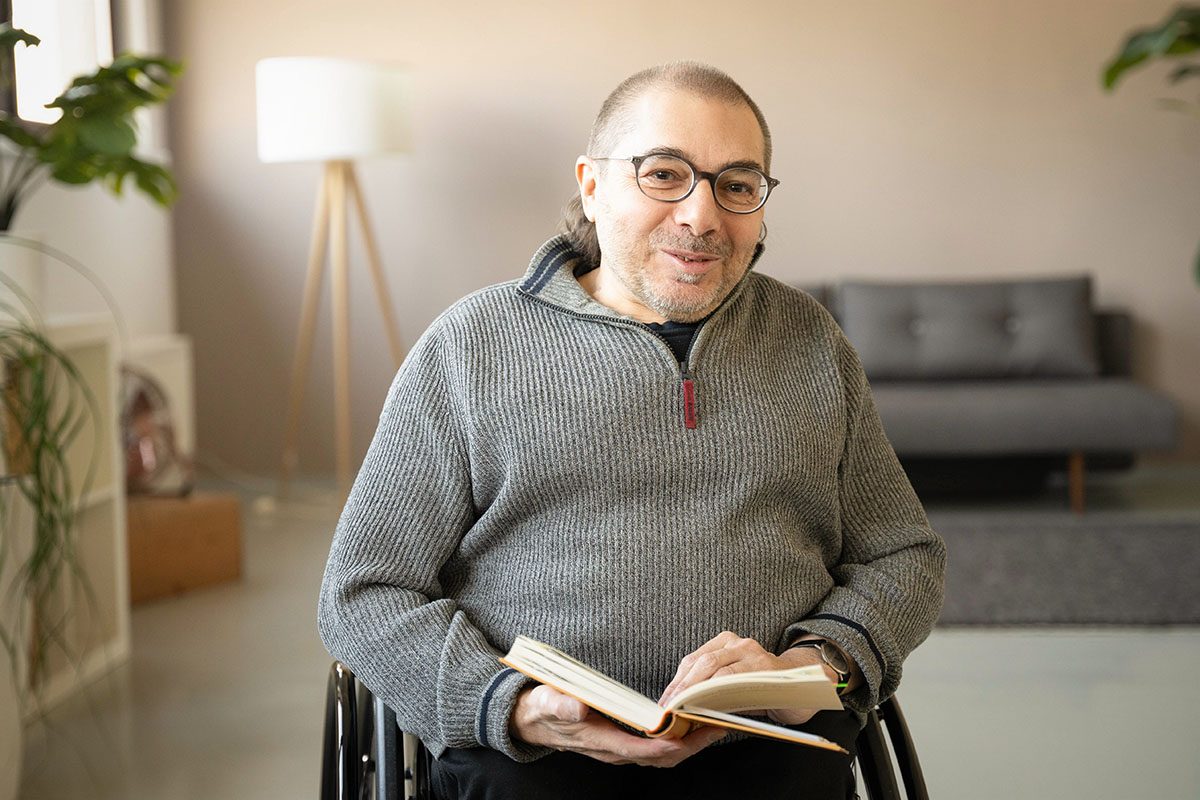 Andreas Bergmann sitzt im Rollstuhl Portrait mit Buch